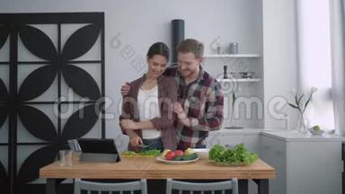 一对爱笑的情侣在美食中的画像，快乐的女孩和男人一起准备健康的食物和新鲜的蔬菜